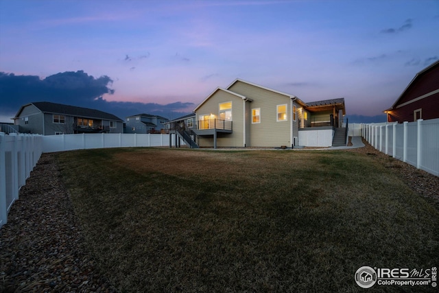 back of house with a fenced backyard, a lawn, and stairs