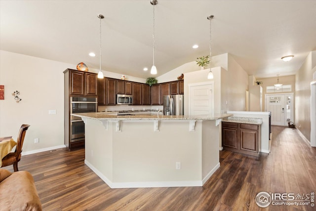 kitchen with a breakfast bar area, stainless steel appliances, dark wood-style floors, a large island, and dark brown cabinets