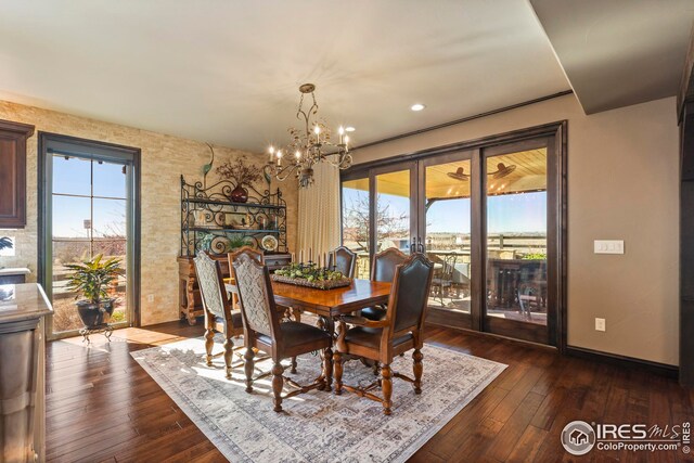 dining area with plenty of natural light, baseboards, a notable chandelier, and dark wood-type flooring