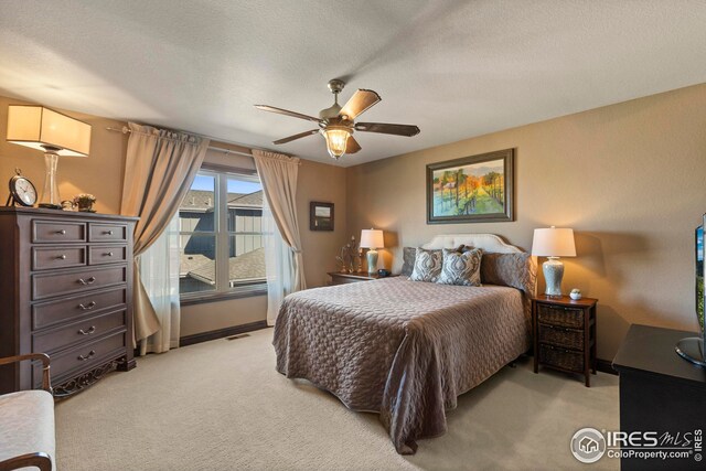 bedroom with a ceiling fan, light carpet, a textured ceiling, baseboards, and visible vents