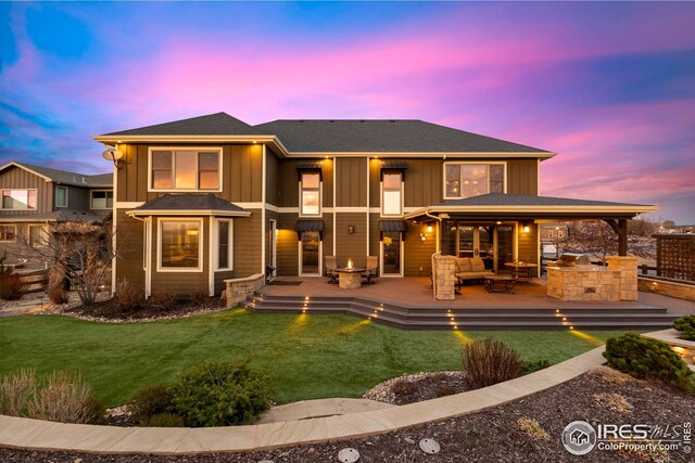 rear view of property featuring an outdoor living space, exterior kitchen, board and batten siding, and a yard