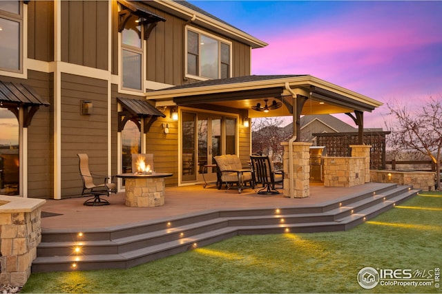 exterior space with an outdoor fire pit, board and batten siding, and a deck