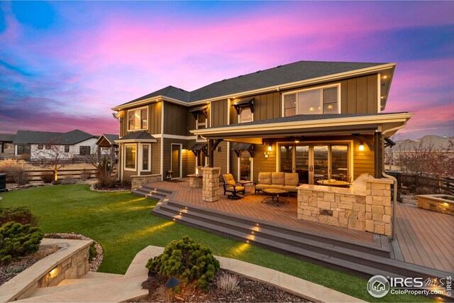 rear view of property with stone siding, board and batten siding, a deck, outdoor lounge area, and a yard