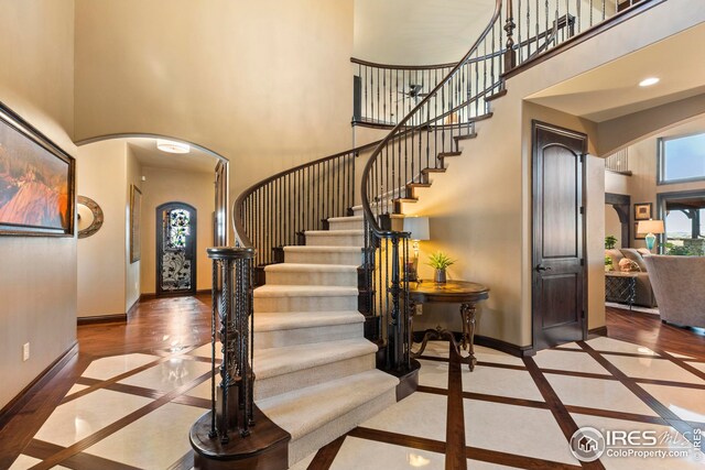 entrance foyer with stairs, a high ceiling, baseboards, arched walkways, and recessed lighting