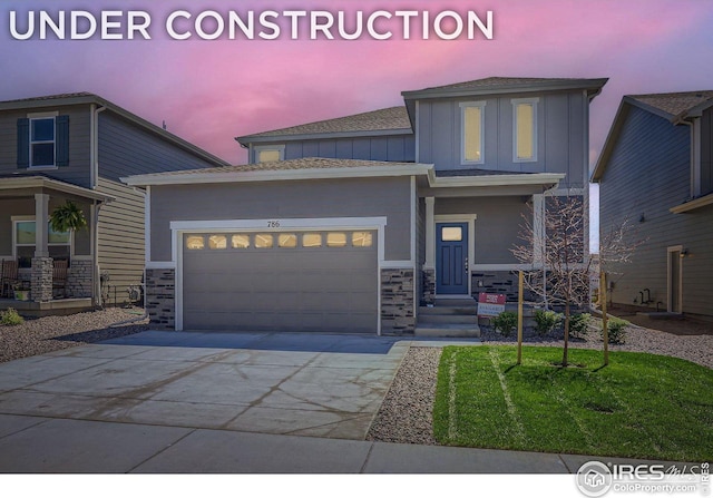 786 Griffith St, Lochbuie, CO 80603 - view of front of home featuring board and batten siding, concrete driveway, an attached garage, stone siding, and a front yard