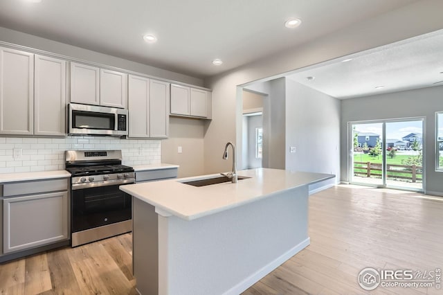 786 Griffith St, Lochbuie, CO 80603 - kitchen featuring stainless steel appliances, a sink, light countertops, light wood finished floors, and tasteful backsplash