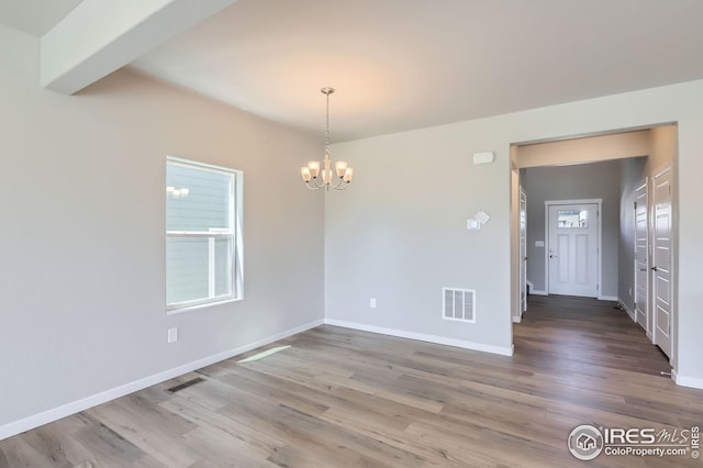 786 Griffith St, Lochbuie, CO 80603 - unfurnished dining area with a chandelier, wood finished floors, and baseboards