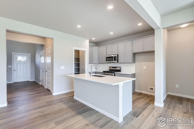 786 Griffith St, Lochbuie, CO 80603 - kitchen with appliances with stainless steel finishes, a sink, light countertops, decorative backsplash, and light wood-style flooring