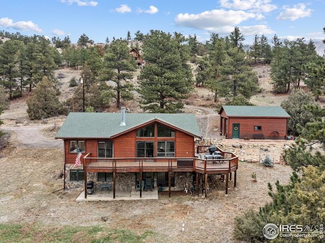 rear view of house with stone siding, a wooden deck, and a patio area