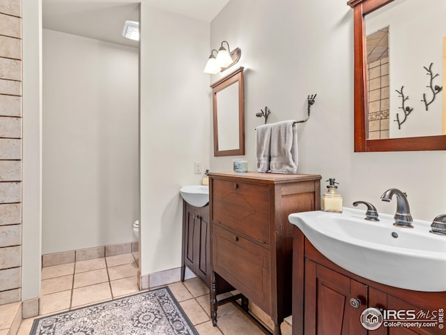 full bath featuring a sink, tile patterned floors, toilet, and two vanities