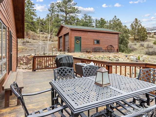 wooden deck featuring outdoor dining area and an outbuilding