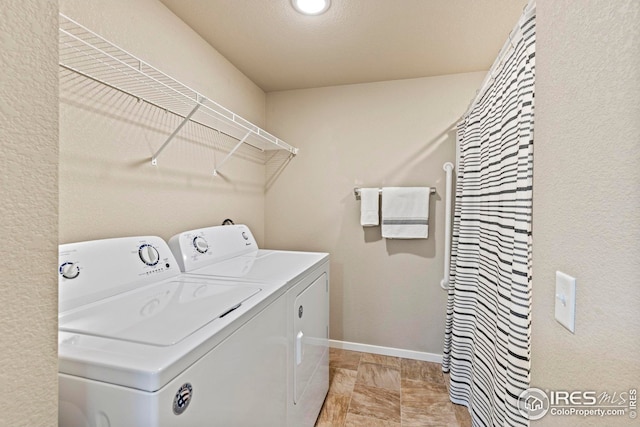 clothes washing area with baseboards, laundry area, and separate washer and dryer