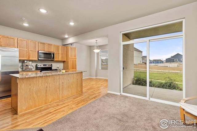 kitchen featuring plenty of natural light, appliances with stainless steel finishes, light stone counters, and light brown cabinetry