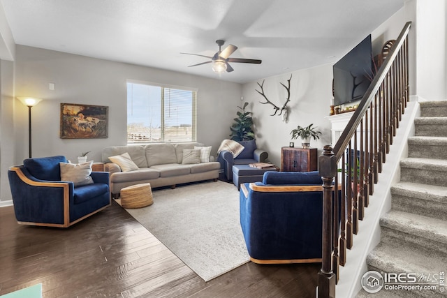 living area featuring a ceiling fan, stairway, wood finished floors, and a fireplace