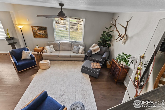 living room featuring wood finished floors, ceiling fan, baseboards, and a textured ceiling