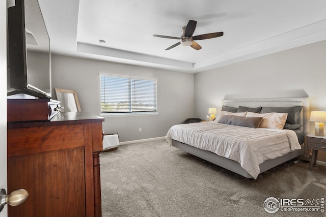 bedroom with baseboards, a tray ceiling, dark colored carpet, and ceiling fan