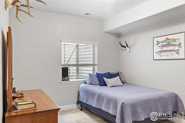 bedroom featuring light carpet, a desk, and baseboards
