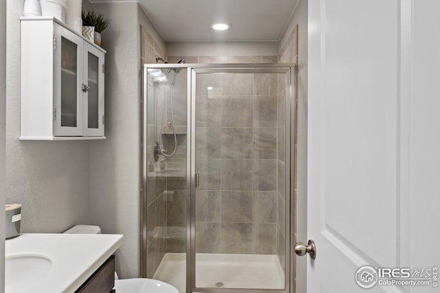 full bath with a shower stall, vanity, toilet, and a textured wall