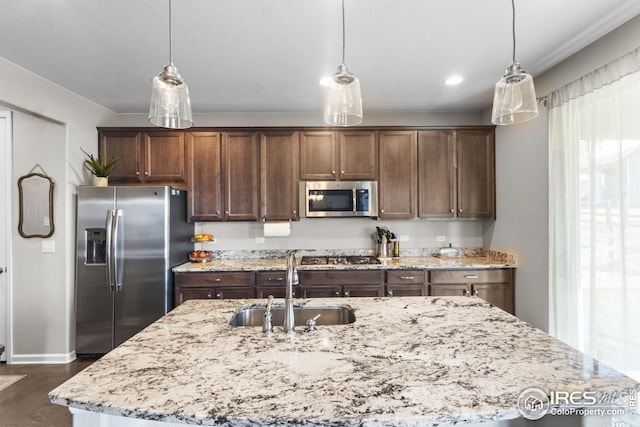 kitchen with appliances with stainless steel finishes, a sink, dark wood-type flooring, light stone countertops, and recessed lighting