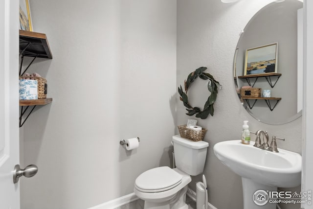 bathroom featuring toilet, baseboards, and a sink