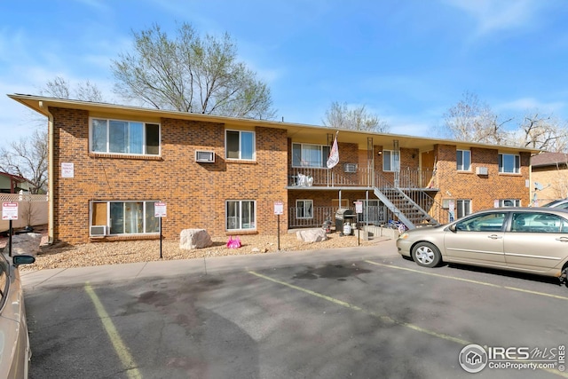 view of building exterior featuring uncovered parking and a wall unit AC