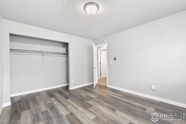unfurnished bedroom with a closet, baseboards, a textured ceiling, and wood finished floors