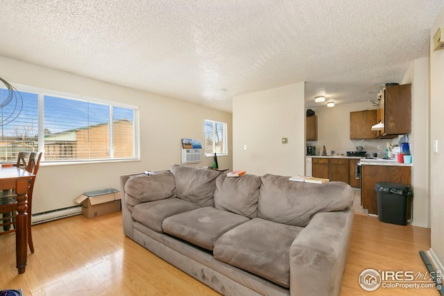 living room featuring baseboard heating, light wood-style flooring, and a textured ceiling