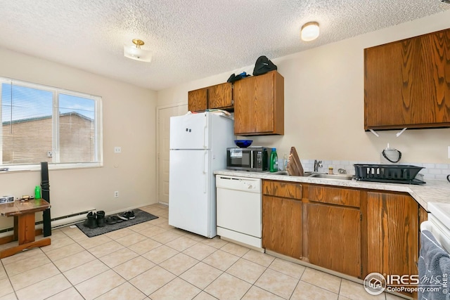 kitchen with light countertops, a sink, brown cabinets, and white appliances