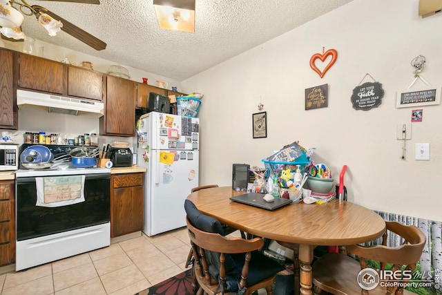 kitchen with light countertops, light tile patterned floors, under cabinet range hood, and white appliances