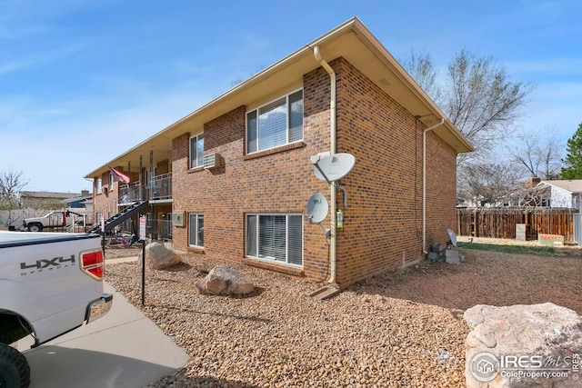 view of property exterior featuring fence and brick siding