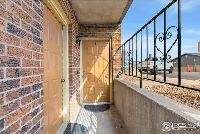 property entrance featuring a balcony and brick siding