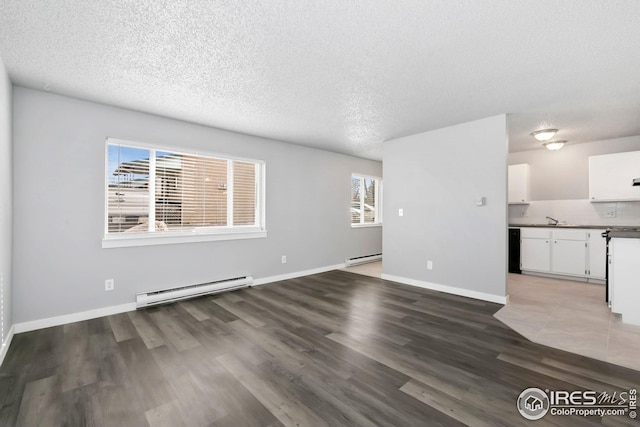 unfurnished living room featuring wood finished floors, a textured ceiling, baseboards, and baseboard heating