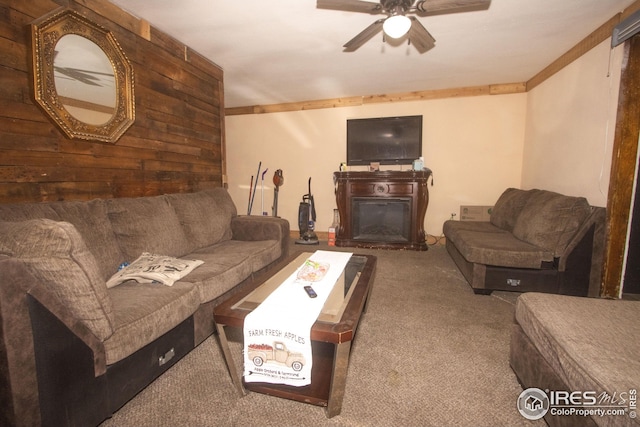 carpeted living room with wood walls, a fireplace, and ceiling fan