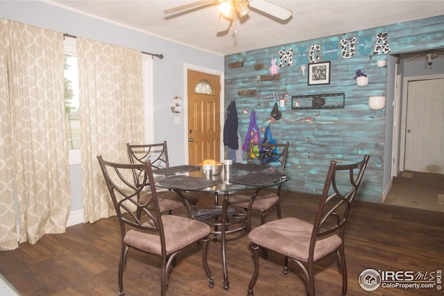 dining room featuring wood finished floors, an accent wall, and a ceiling fan