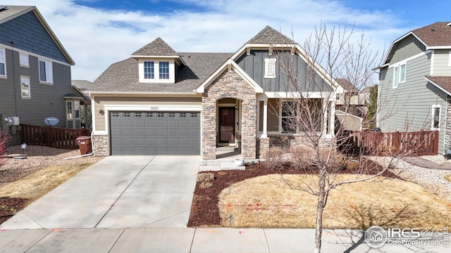 craftsman-style home featuring a garage, fence, stone siding, roof with shingles, and concrete driveway