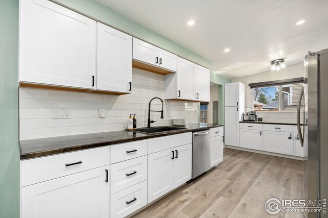 kitchen featuring decorative backsplash, stainless steel appliances, white cabinets, and a sink