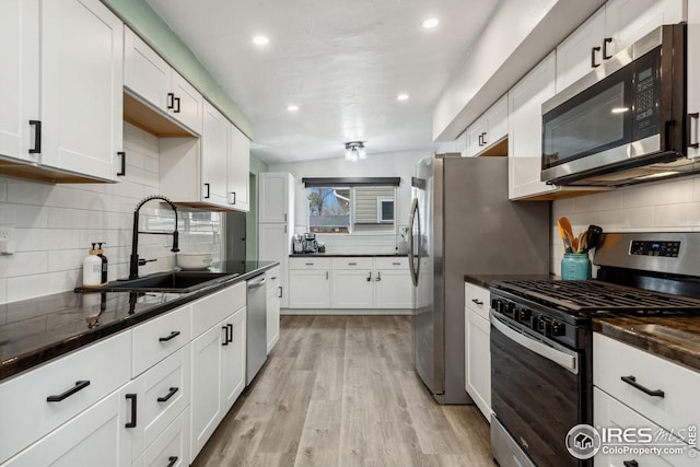 kitchen featuring tasteful backsplash, appliances with stainless steel finishes, white cabinetry, and a sink