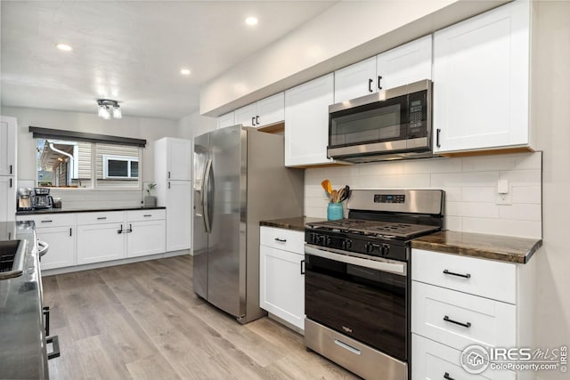 kitchen with decorative backsplash, dark countertops, stainless steel appliances, and white cabinetry
