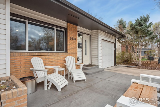 view of patio featuring concrete driveway and a garage