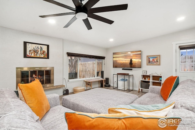 living room with vaulted ceiling, wood finished floors, a glass covered fireplace, ceiling fan, and recessed lighting