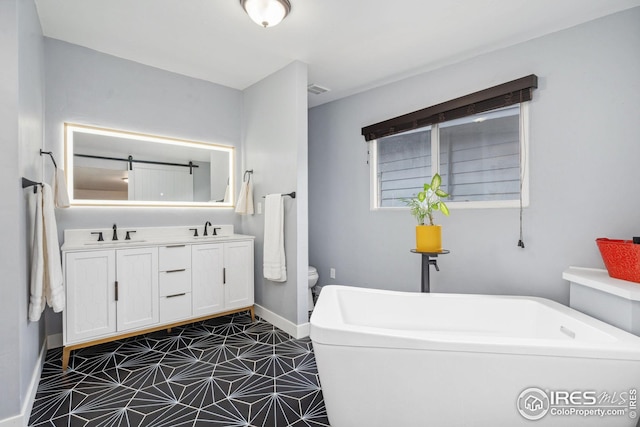 full bathroom with baseboards, a freestanding tub, a sink, and toilet