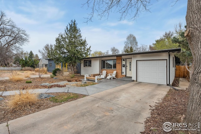 ranch-style home featuring a garage, concrete driveway, and fence