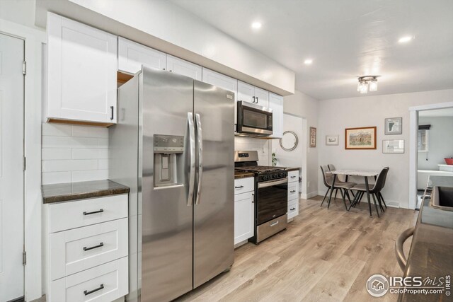kitchen featuring white cabinets, decorative backsplash, light wood finished floors, and stainless steel appliances