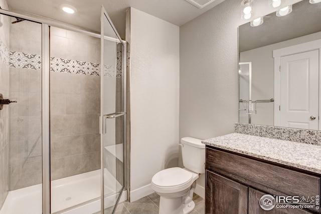 bathroom with vanity, baseboards, a stall shower, tile patterned flooring, and toilet