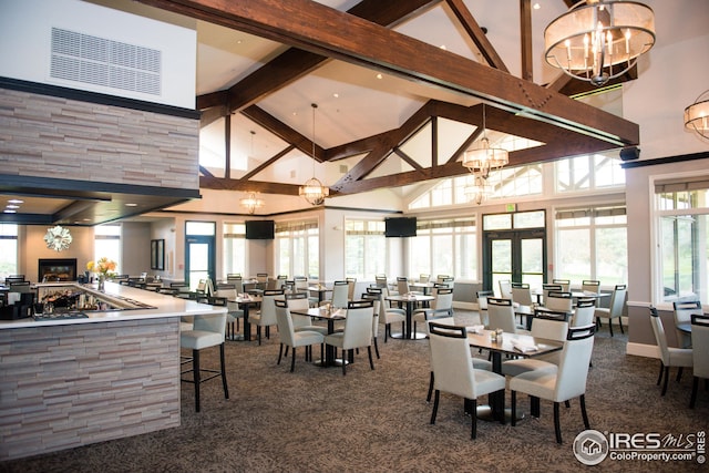 carpeted dining space with beamed ceiling, high vaulted ceiling, and a notable chandelier