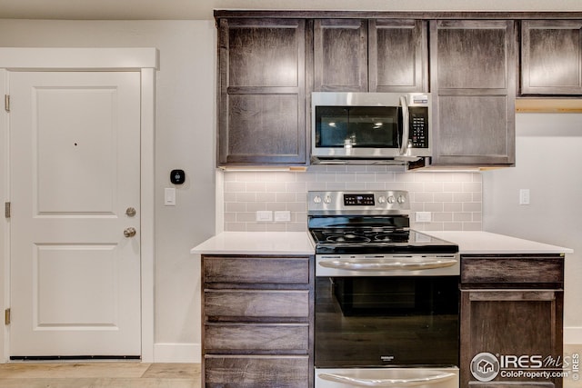 kitchen featuring stainless steel appliances, light countertops, dark brown cabinets, and decorative backsplash