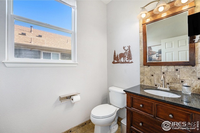 bathroom with toilet, baseboards, tile patterned flooring, tasteful backsplash, and vanity