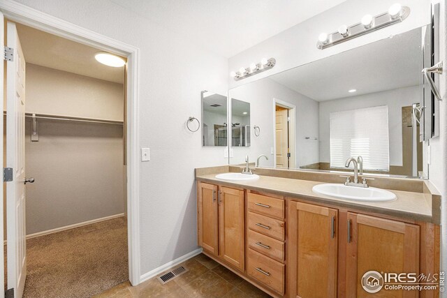 bathroom featuring a sink, double vanity, a spacious closet, and visible vents