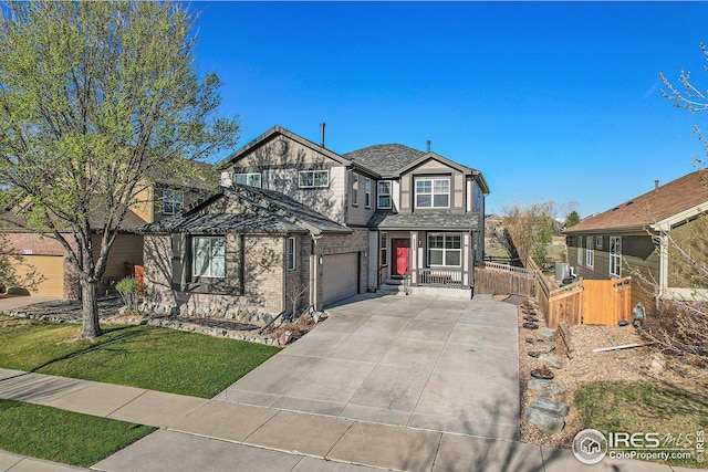 view of front of house featuring a garage, fence, concrete driveway, a front yard, and brick siding