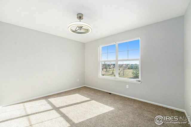 carpeted empty room featuring baseboards and visible vents